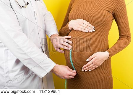 Happy Beautiful Pregnant Young Woman Touching Her Bare Tummy While A Doctor Is Measuring It