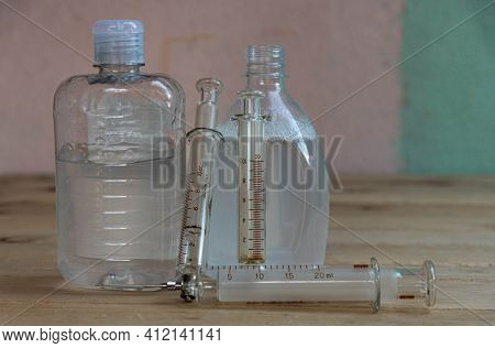 Bottles Of Alcohol Gel And Syringes On Wooden Background