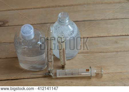 Bottles Of Alcohol Gel And Syringes On Wooden Background