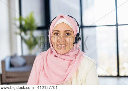 Headshot Of Young Muslim Arab Mixed-race Woman In Hijab And Headset Sitting In The Office With Panor