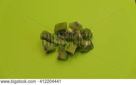 Pile Of Chopped Fresh Kiwi Fruit On Plain Green Background With Copyspace