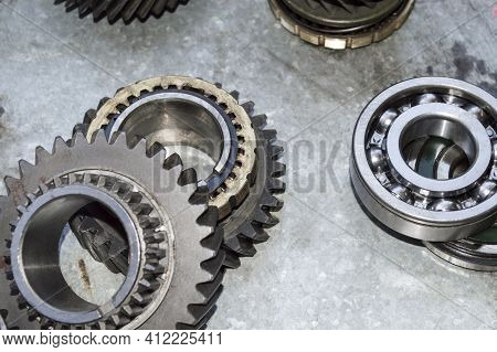 The Gears And Bearings Of The Car's Manual Transmission Lie On A Metal Worktable In The Auto Repair 