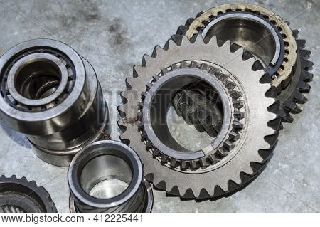 The Bearings And Gears Of The Car's Manual Transmission Lie On A Metal Worktable In The Auto Repair 