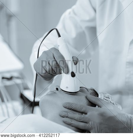 Young Woman Getting Chromotherapy Procedure For Face Skin Rejuvenation. Black And White Image With B