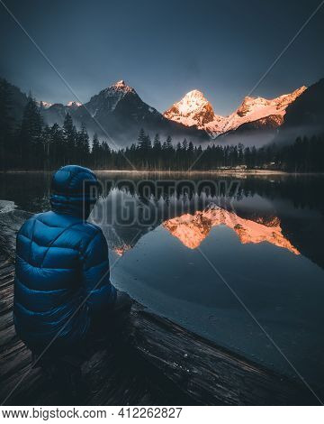 Person Sitting At Mountain Lake Watching Sunrise During Spring