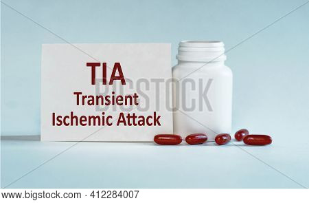 On A Light Blue Background A Card With The Text Tia - Transient Ischemic Attack Near The White Bottl