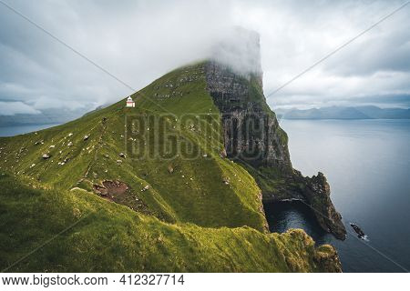 Kalsoy Island With Kallur Lighthouse On On Faroe Islands, Denmark, Europe. Clouds Over High Cliffs, 