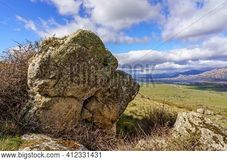 Green Landscape With Big Rocks, Lake And Mountains In The Background And White Clouds On Blue Sky. N