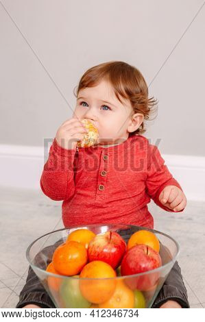 Cute Adorable Caucasian Baby Boy Eating Citrus Fruits. Finny Child Eating Healthy Organic Snack For 