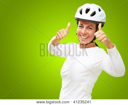 Femme portant casque montrant le pouce en haut isolé sur fond vert