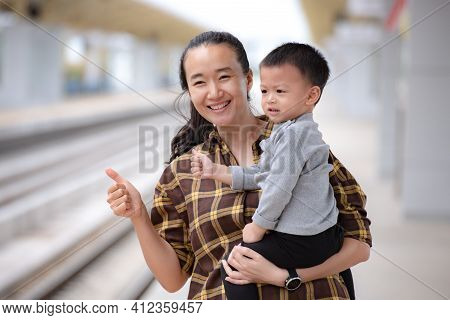 Asian Mother And Child Waiting For Atrain At The Train Platform.they Are Happy To Go Out To Travel.t