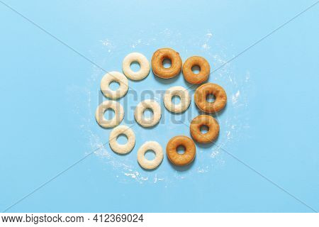 Making Donuts Recipe. Uncooked Yeast-raised Dough In Circle Shape And Fried Doughnuts, On A Blue Bac