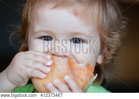 Baby Eating Bun Bread. Close Up Face. Cute Toddler Child Eating Sandwich, Self Feeding Concept