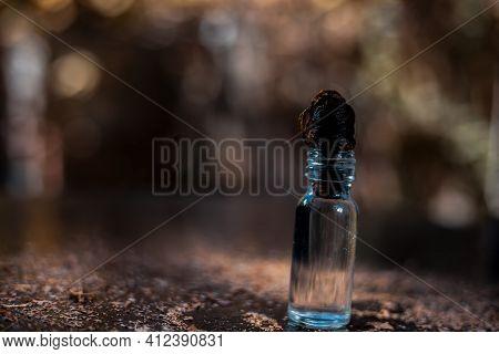 Shot Of Glycerine Bottle On A Black-colored Shiny Wooden Surface.