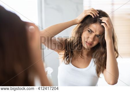 Unhappy Woman Looking At Hair Flakes Having Dandruff Problem Indoor