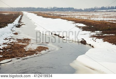 River In Early Spring On The Bank Of Snow. The Snow Melts With The Arrival Of Heat Near The Banks Of