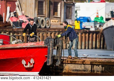 Prague, Czech Republic - February 18, 2021. Two Workes On The Ship Tie The Ponton To The Red Boat By
