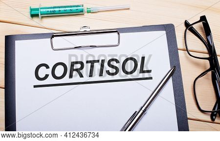 The Word Cortisol Is Written On A White Piece Of Paper Next To Black-rimmed Glasses, A Pen And A Syr