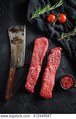Raw Marbled Beef Steak Near Butcher Knife With Pink Pepper And Rosemary. Black Background. Top View.