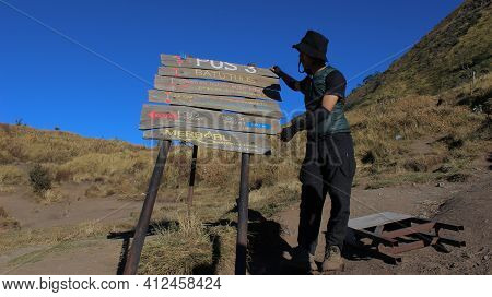 Magelang, Indonesia - 08 06 2019: A Man Climbing Mount Merbabu Finds A Signpost And Captures The Mom