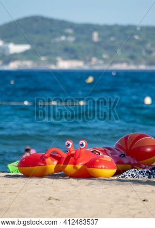 Family Summer Vacation On French Riviera, France, View On Blue Sea, Sandy Beach And Red Inflatable F