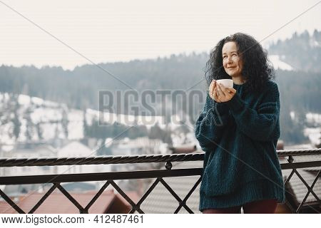 Middle-aged Woman Drinking Coffee On Balcony In Winter Alone