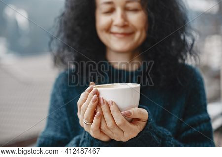 Middle-aged Woman Drinking Coffee On Balcony In Winter Alone