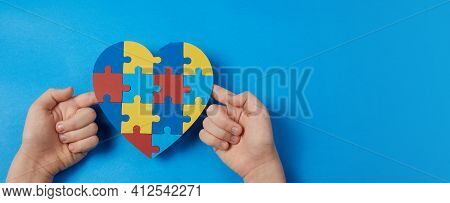 Autistic Boy Hands Holding Jigsaw Puzzle Heart Shape. Autism Spectrum Disorder Family Support Concep