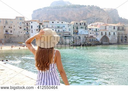 Summer Holiday In Italy. Back View Of Young Woman With Straw Hat And Striped Dress With Cefalu Villa