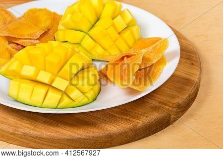 Dried Slices Of Mango Pulp And Cut Fresh Mango Halves On White Dish On A Wooden Serving Board, Fragm