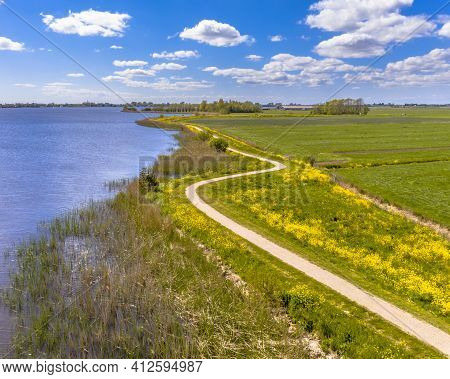 Aerial Springtime Scene Of Dutch River Near Boornzwaag. Cycling Track On Dike Meandering Throug Pold