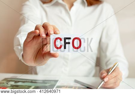 A Woman In A White Shirt Holds A Piece Of Paper With The Text: Cfo. Business Concept For Companies. 