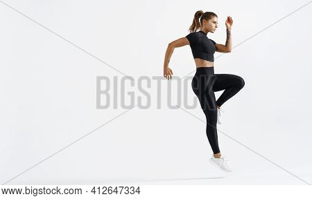Determined Healthy Woman Doing Workout On White Background. Fitness Trained Female Raising Leg And J
