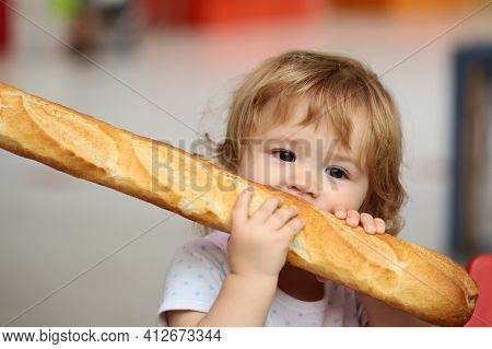 Cute Baby Eating French Baguette White Bread. Funny Toddler Child Eating Sandwich, Self Feeding Conc