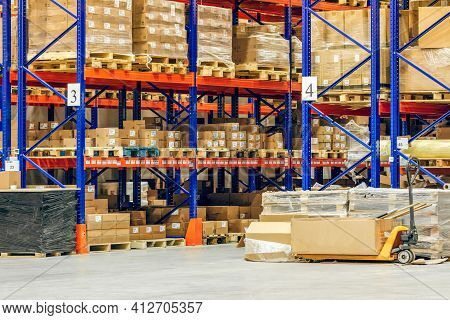 Interior Of A Modern Warehouse Storage Of Retail Shop With Pallet Truck Near Shelves