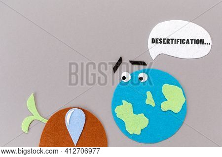 Desertification. Cutted Out Of Felt The Planet With Emoticon And Dry Soil With A Dead Plant Sprout. 