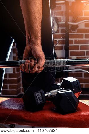 Female Personal Trainer Helping A Young Man Lift Dumbells While Working Out In A Gym