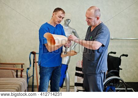 Two Prosthetist Man Workers With Prosthetic Leg Working In Laboratory.