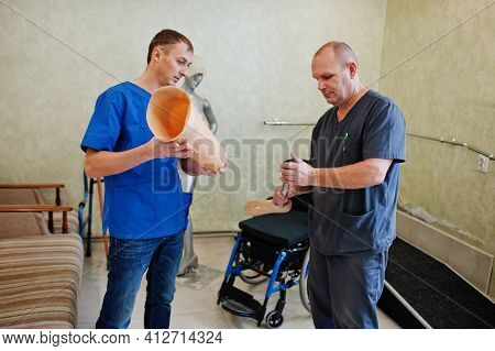 Two Prosthetist Man Workers With Prosthetic Leg Working In Laboratory.