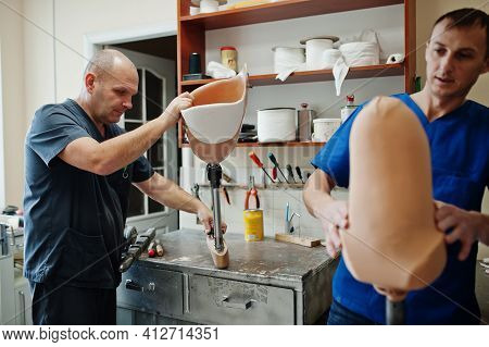 Two Prosthetist Man Workers Making Prosthetic Leg While Working In Laboratory.