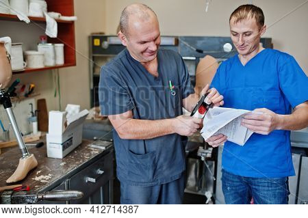 Two Prosthetist Man Workers Making Prosthetic Leg While Working In Laboratory.