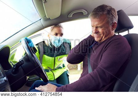 Female Paramedic Helping Mature Male Driver With Whiplash Injury Involved In Road Traffic Accident