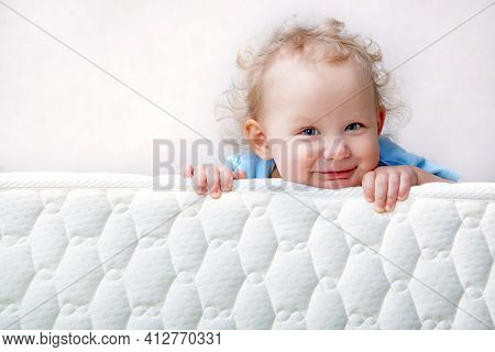 Baby On The Bed Mattress Close-up. The Sidewall Of The Mastras Is Stitched With Finishing Lines.