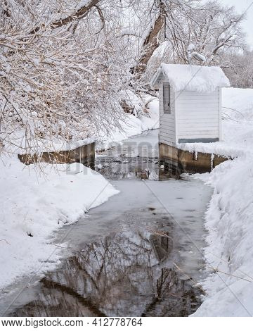 Boxelder Ditch diverting water from the Poudre RIver and water guage after heavy snowstorm in Fort Collins, northern Colorado
