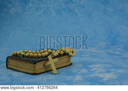 Bible Book With Rosary Beads On Blue Background