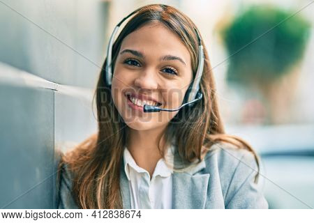 Young latin call center aget girl smiling happy using headset at the city.