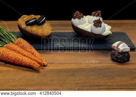 Chocolate Easter Eggs On Top Of Black Stone With Wooden Background