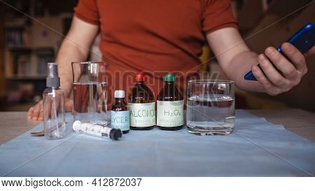 A Middle Aged Man Reading Receipt From Mobile Phone And Doing Hand Sanitizer At Home