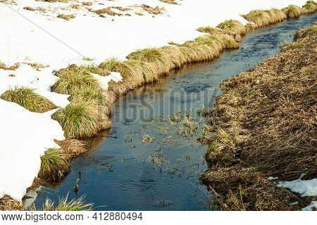 River In Early Spring On The Bank Of Snow. The Snow Melts With The Arrival Of Heat Near The Banks Of