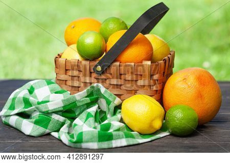 Variuos citrus fruits in basket on garden table. Oranges, lemons, limes and grapefruit